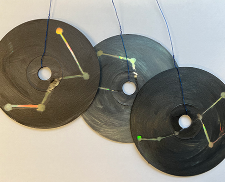 CDs painted a glittery black with constellations etched out hanging from wire